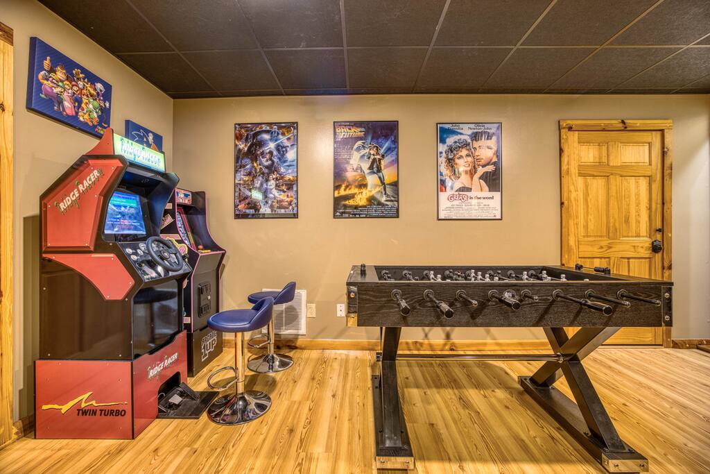 Dive into fun at our cabin’s game room! Enjoy a vintage arcade game with Ridge Racer and a sleek foosball table for epic matches. Retro movie posters add nostalgia, perfect for family nights or friend gatherings. Dive into fun at our cabin’s game room! Enjoy a vintage arcade game with Ridge Racer and a sleek foosball table for epic matches. Retro movie posters add nostalgia, perfect for family nights or friend gatherings. - Spacious Cabin, Hot Tub, Theater, Dog Run, FirePit - Ellijay