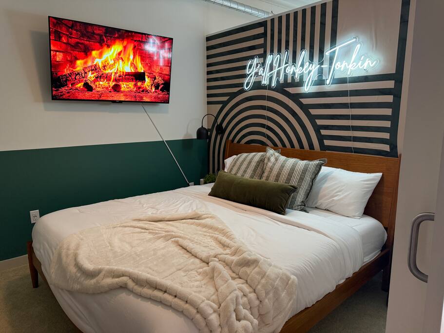 Bedroom | Neon Sign + Cozy Fireplace Vibe | Main Floor
Get comfy under the “Y’all Honky Tonkin’” neon glow in this stylish bedroom, complete with a plush bed, modern accent wall, and electric fireplace ambiance.