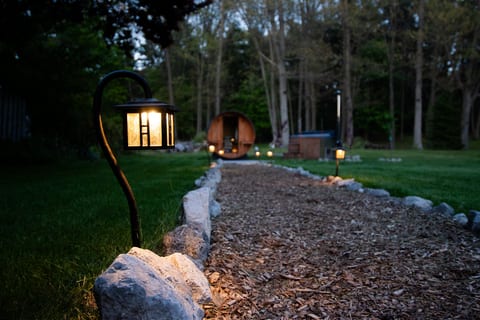 Lit garden path leading to a private sauna and hot tub retreat