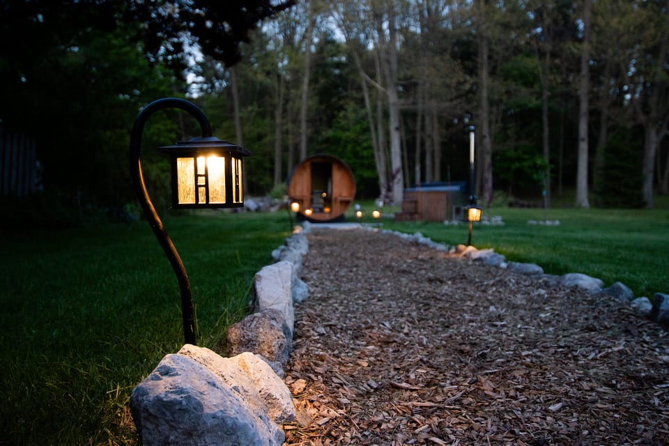 Lit garden path leading to a private sauna and hot tub retreat