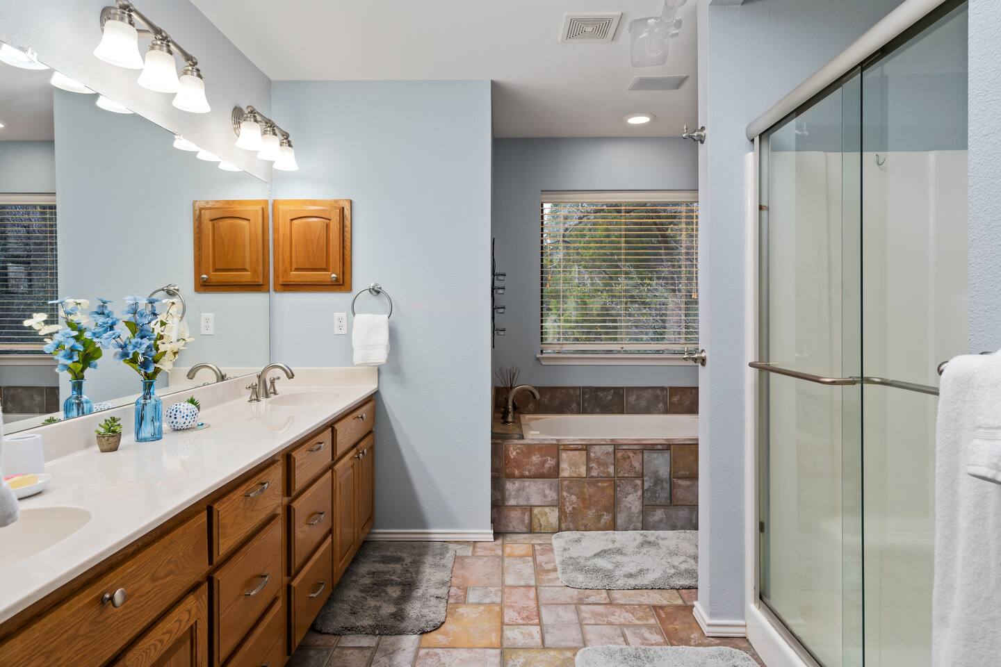 Mid-level primary full bathroom ensuite with double vanity sinks + tub + sliding shower - Infinite Views, Heated Pool, Hill Country Paradise! - Canyon Lake