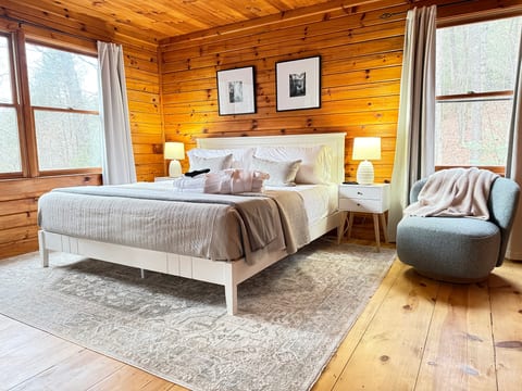 Cozy cabin bedroom with king bed, warm wood, and forest views.