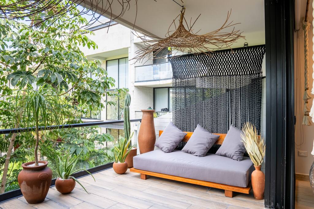 Terrace adorned with exotic plants and a spacious, Japanese wabi sabi sofa, perfect for relaxation and enjoyment.