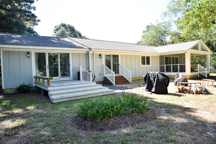 Back of house [deck to primary suite, firepit, propane grill, screened-in porch.]