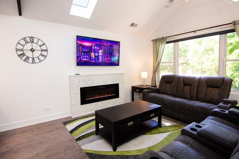 Bright living room with recliners, fireplace, TV, and abundant natural light