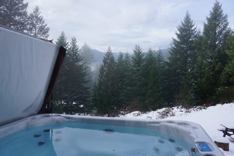 Indulge in ultimate relaxation as you soak in our luxurious hot tub, surrounded by panoramic mountain vistas by day and a canopy of twinkling stars by night, creating an unforgettable experience 
