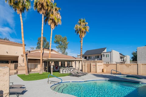 Resort-style pool, shaded cabana & loungers beneath tall palms.