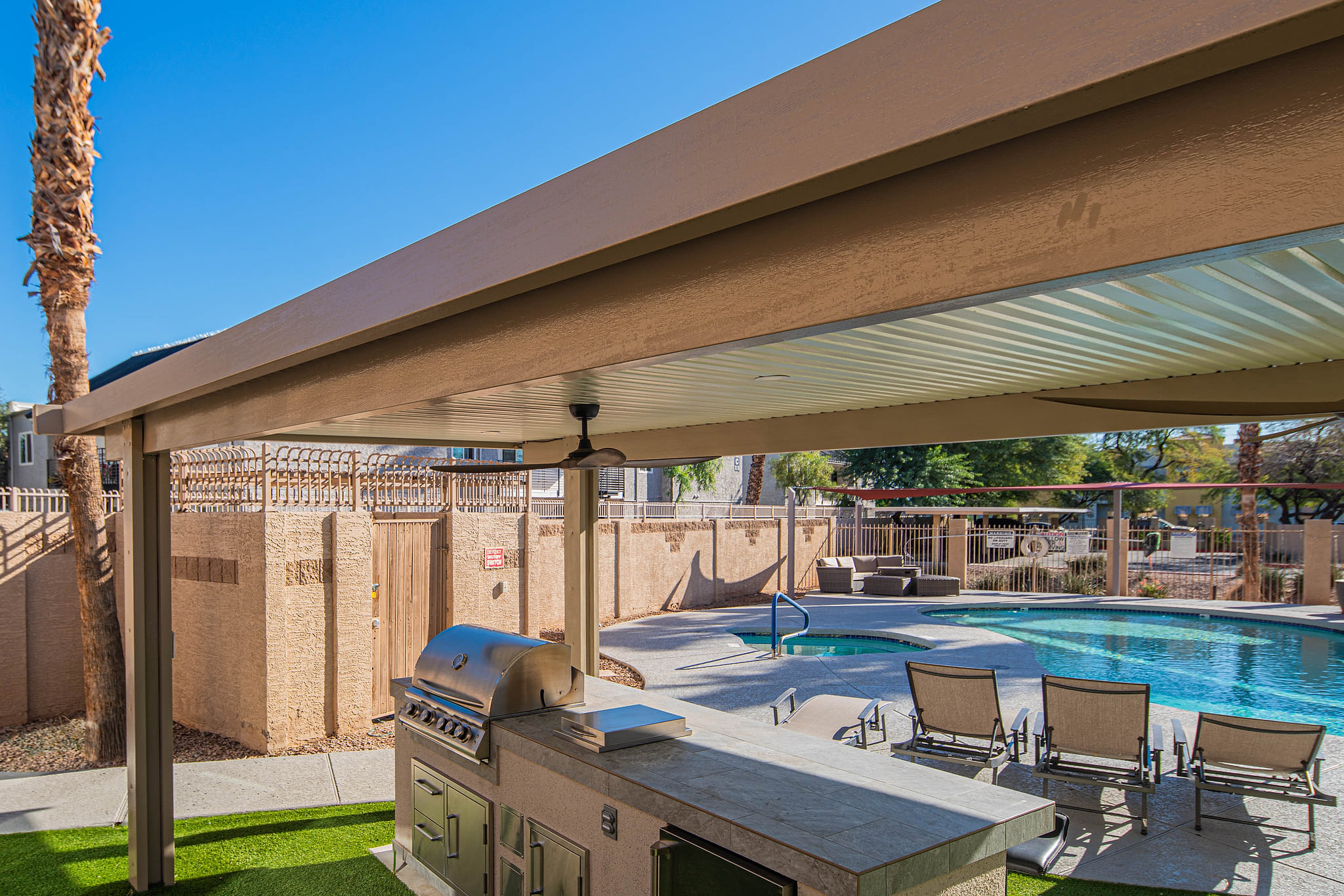 Resort-style pool, shaded outdoor kitchen with grill and loungers