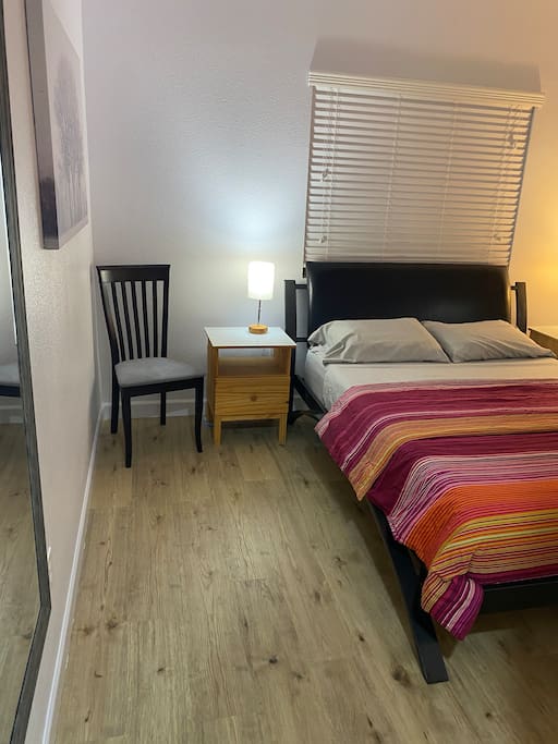 Small bedroom with queen bed and hardwood floors.