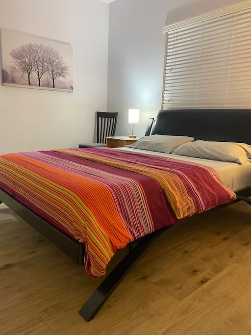 Small bedroom with queen bed and hardwood floors.