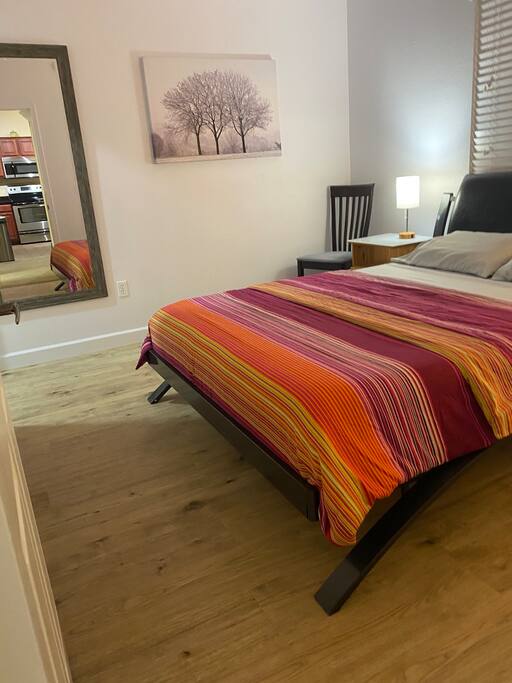 Small bedroom with queen bed and hardwood floors.