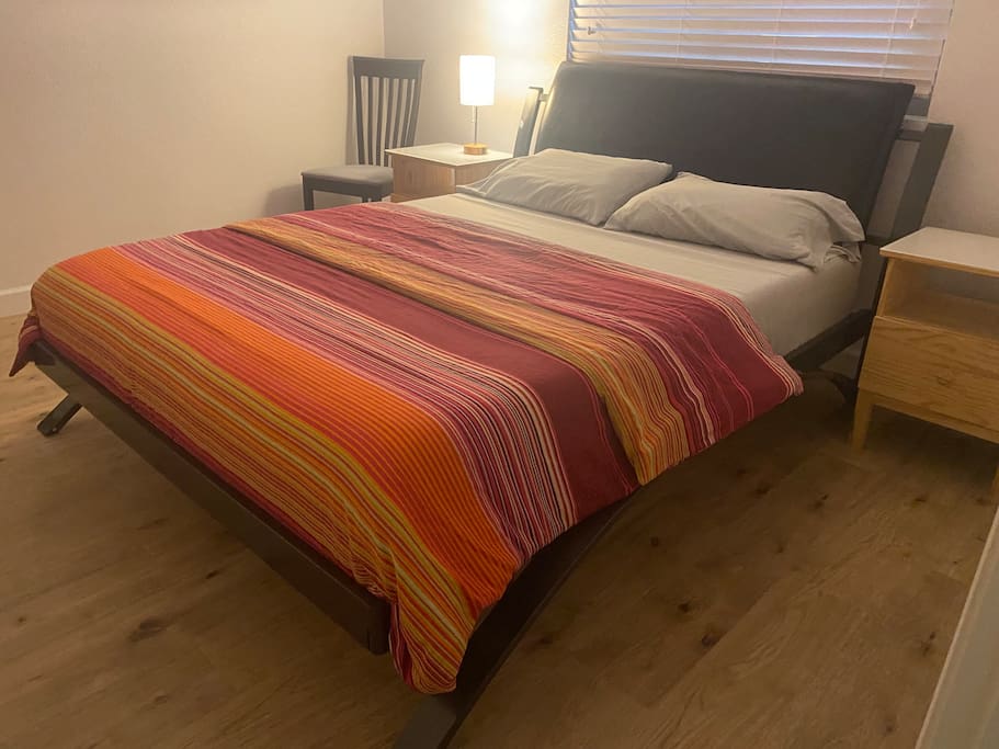 Small bedroom with queen bed and hardwood floors.