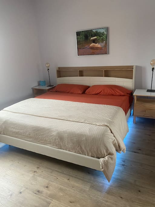 Floating King bed in master bedroom with hardwood floors.