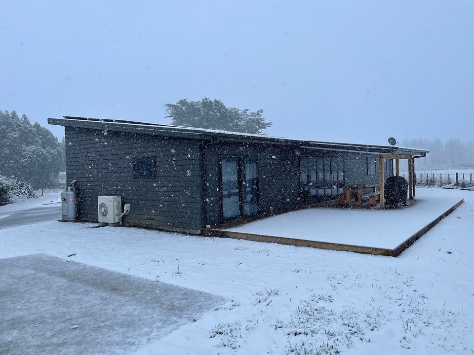 Modern house with covered deck in a peaceful snowy setting