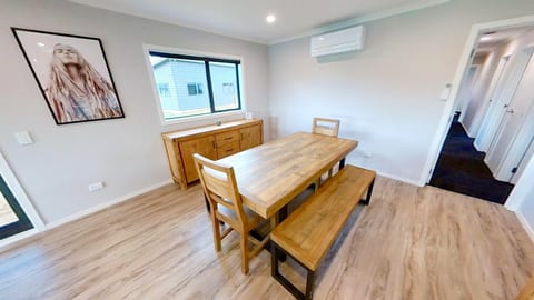 Bright modern dining space with timber table, bench seating, and A/C