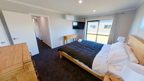 Bright modern bedroom with TV, AC, and sliding door for natural light