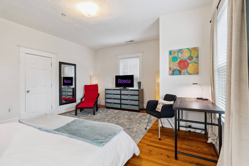 The upstairs king bedroom also includes a TV, reading chair, and dresser, making it a spacious and comfortable retreat with room to unpack, unwind, and catch up on work or your favorite shows. The upstairs king bedroom also includes a TV, reading chair, and dresser, making it a spacious and comfortable retreat with room to unpack, unwind, and catch up on work or your favorite shows. - In Southside | Roomy 6 Bedroom | Walk to Choo Choo - Chattanooga