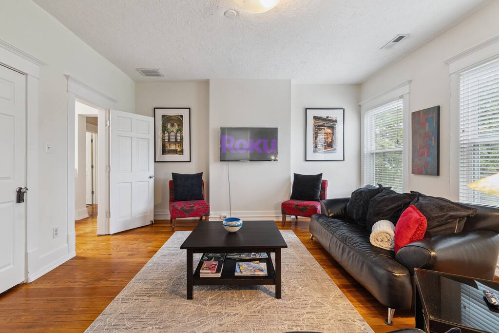 Gather in the cheerful upstairs living room, where large windows, colorful accents, and comfy leather seating create a bright and welcoming space to relax, stream your favorite shows, or enjoy time together. Gather in the cheerful upstairs living room, where large windows, colorful accents, and comfy leather seating create a bright and welcoming space to relax, stream your favorite shows, or enjoy time together. - In Southside | Roomy 6 Bedroom | Walk to Choo Choo - Chattanooga