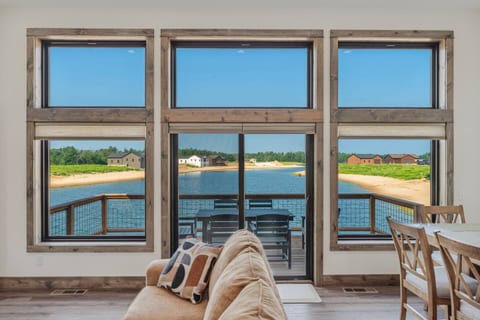Upstairs main living area features a dining area that seats 8, full kitchen with bar seating for 6. a couch and love seat, smart TV with Roku streaming services and a wall of windows/glass sliding door to a full view of Sunset Lake.