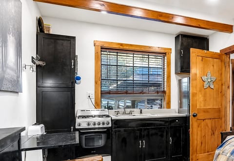 Charming cabin kitchenette with gas range, deep sink, and warm wood accents