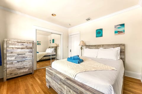 A stylish bedroom with a queen-size bed, dressed in soft linens. A spacious dresser and built-in closet provide plenty of clothing storage. Clean lines, warm tones, and natural light make the space feel calm, organized, and comfortable