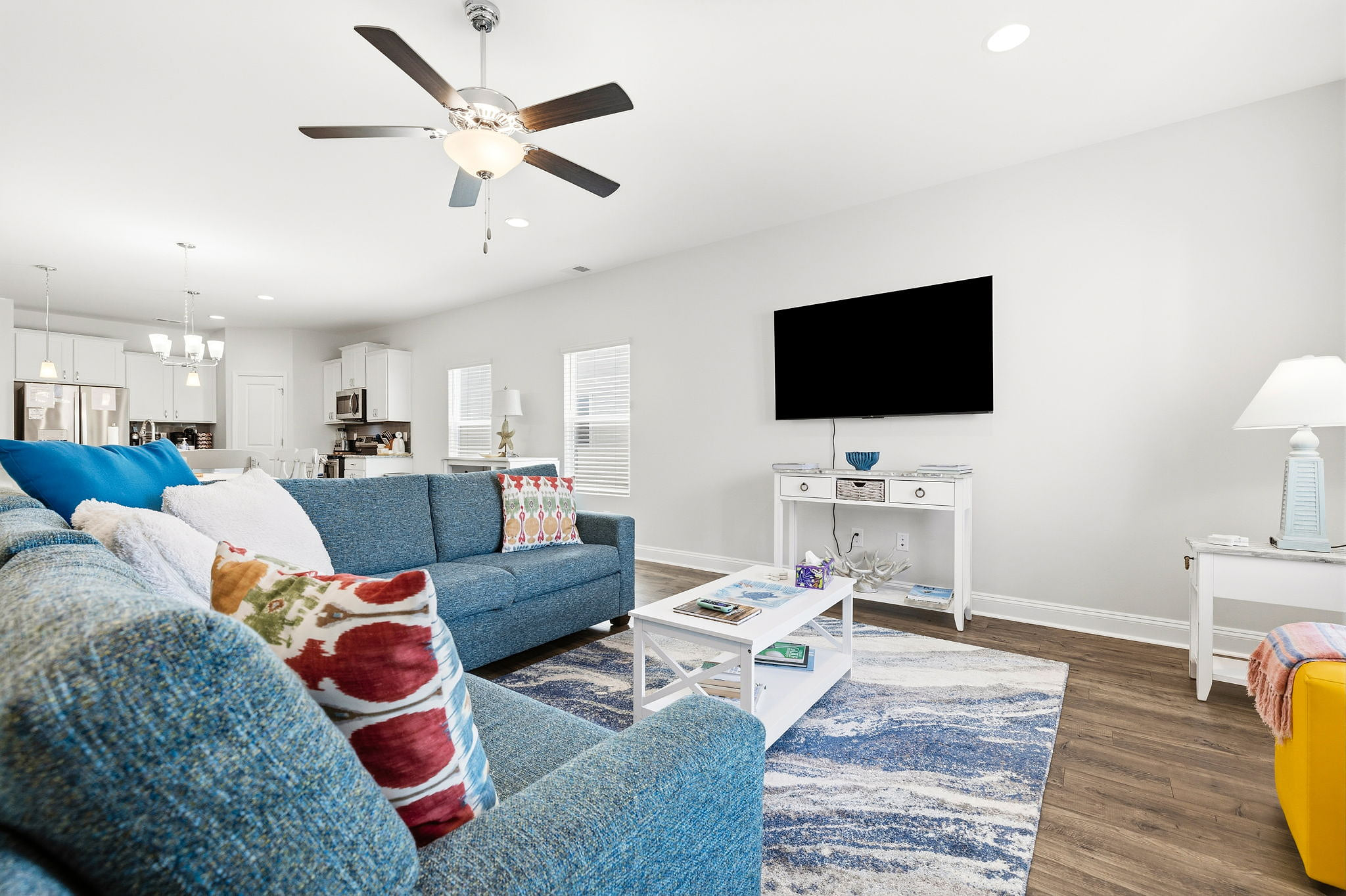 Bright open-plan lounge with blue sofas, smart TV, and coastal charm