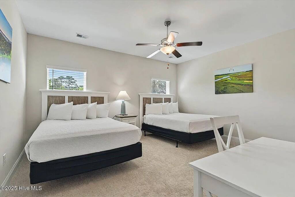 This spacious bedroom offers two queen beds, a ceiling fan for comfort, and a dedicated workspace ideal for remote work or study.