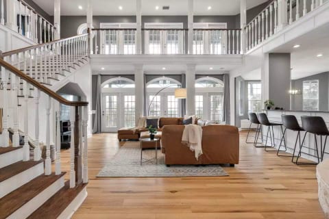 The open concept living room of the main house. You'll immediately notice the vaulted ceilings and the French double doors that flood the room with light, with magnificent views only steps away on the wrap around deck