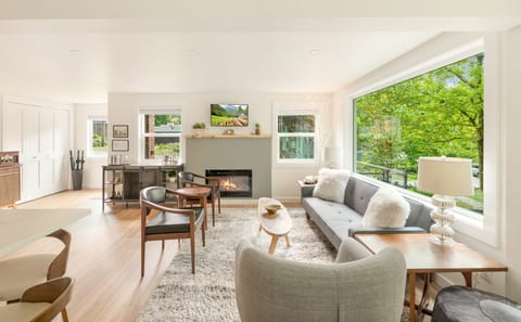 Cozy up in the elegant upper level living room featuring a gas fireplace and a lighted birch tree, perfect for relaxing evenings
