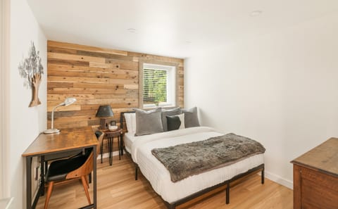 The Wood Room: This cozy bedroom features a comfortable memory foam hybrid mattress and a workspace with office supplies, perfect for any work-from-home needs. A makeup mirror, hairdryer, and full-length mirror are included