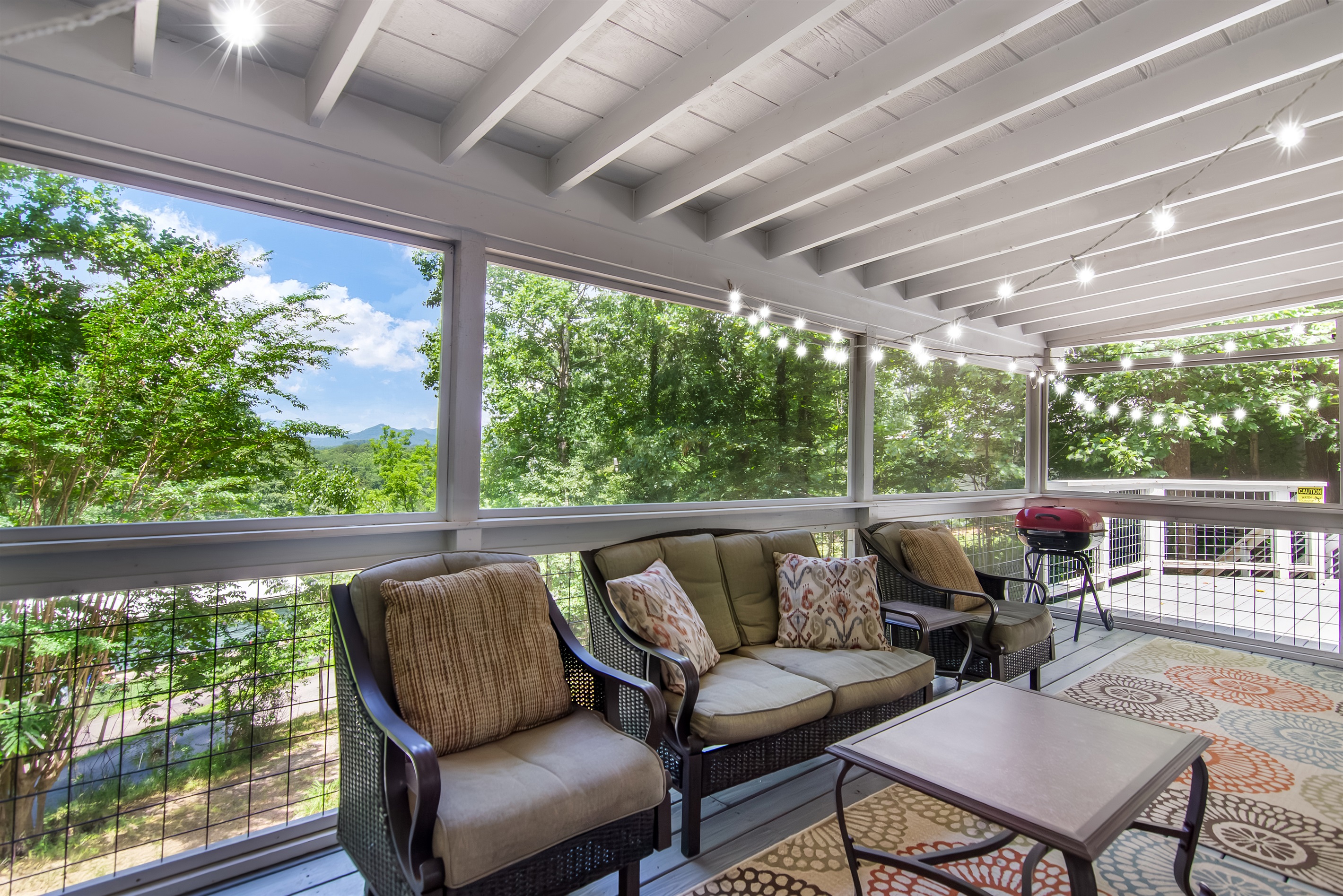 ozy screened-in porch with twinkle lights and forest views