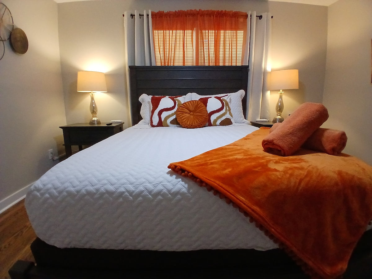 Earthy Comfort 
Orange glow, soft linens, and a warm, welcoming retreat with a queen bed. Equipped with soft lighting, Roku TV, USB charging, and a ceiling fan overhead, just breathe deep and relax.