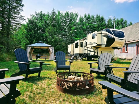 Home base — the 5th wheel set up on full hookups, trees lining two sides of the site.