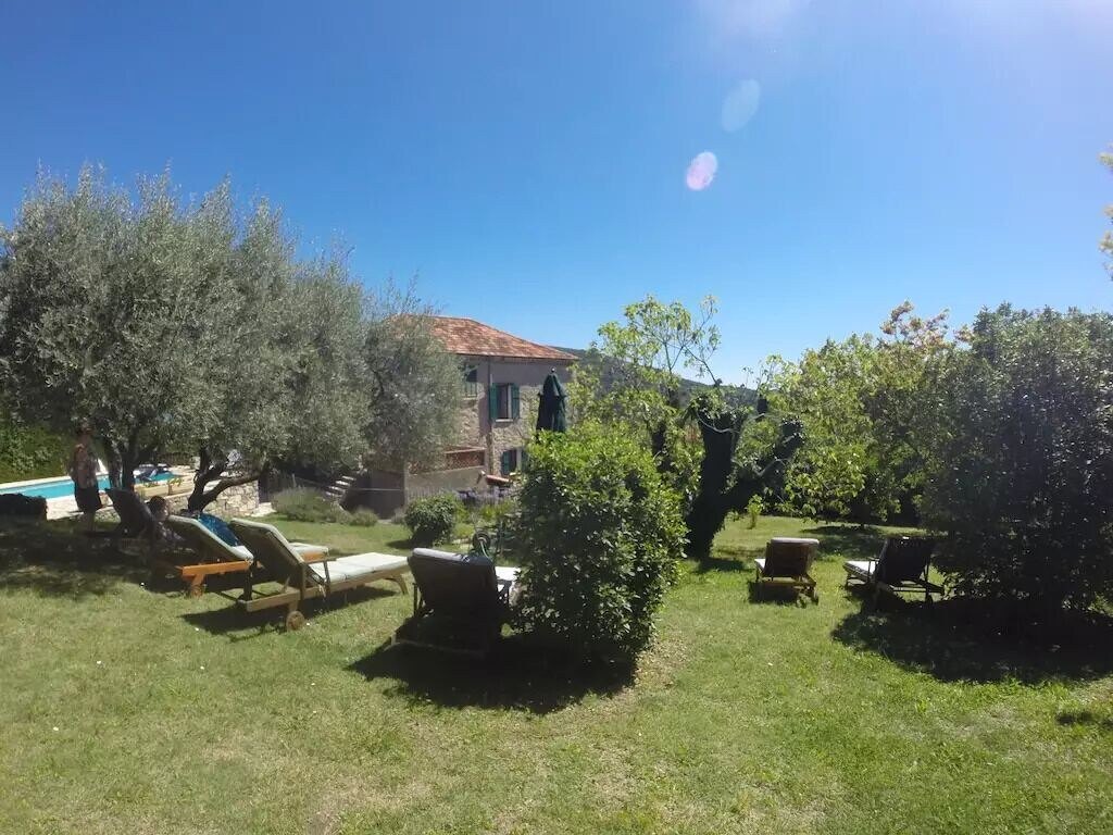 Garden view of house, with olive trees and pool terrace.