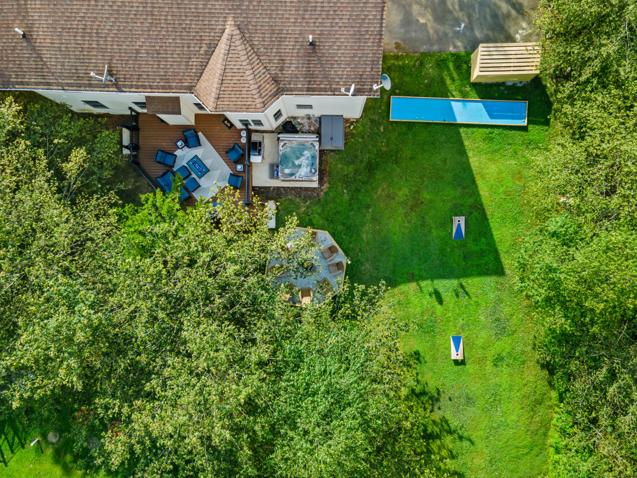 A bird’s-eye view of your ultimate backyard retreat—featuring a spacious deck, firepits, hot tub, and fun outdoor games.