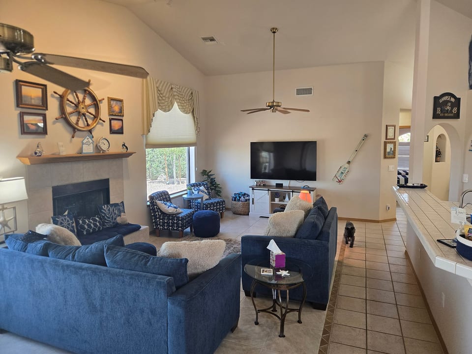 Bright coastal-style living room with fireplace, TV, and plenty of seating