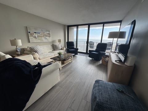 Living room that leads to balcony. Sofa, loveseat and 2 recliners.