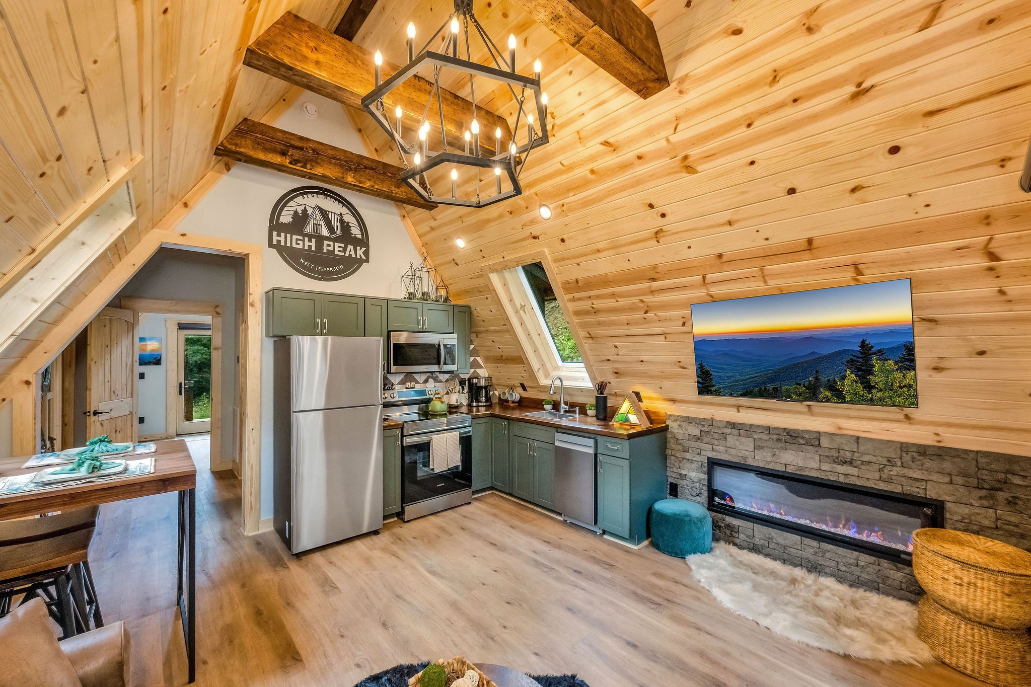 Living area with chandelier, TV, Kitchen and Fireplace Living area with chandelier, TV, Kitchen and Fireplace - High Peak Aframe Cabin - West Jefferson