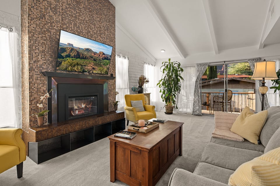 Living room with vaulted ceilings, electric fireplace, smart TV streaming Netflix/Roku, and sliders to a private balcony with red rock views.