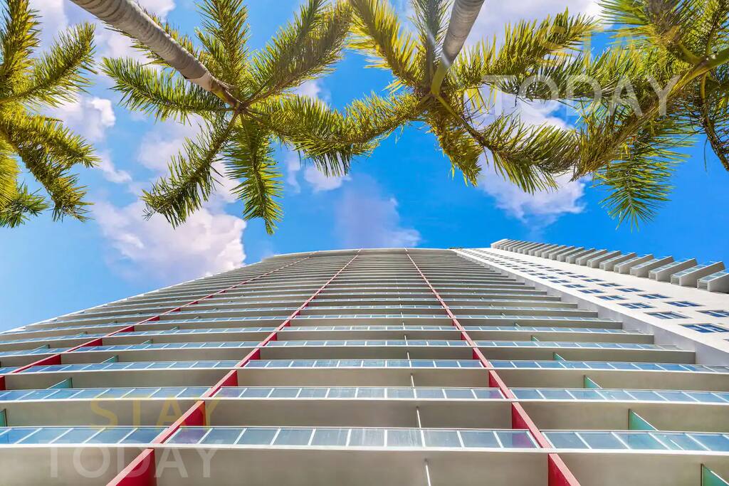 View of the building from the ground showcasing the full height from the ground floor to the top. The angle highlights the windows, offering a sleek, modern look of the building's exterior.