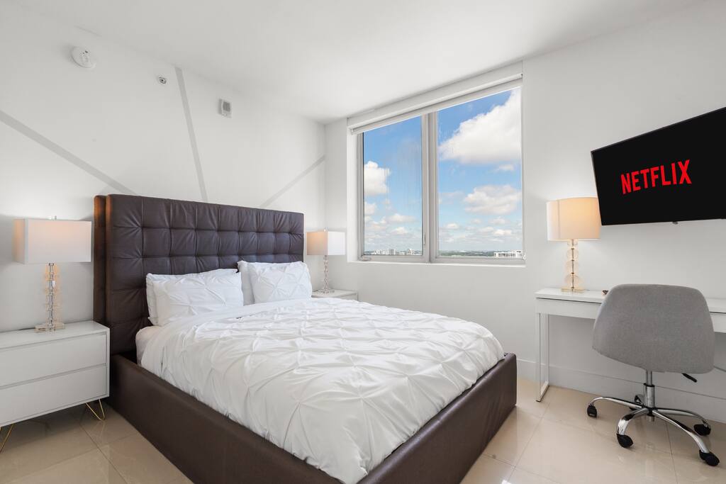 Step into a bright bedroom with a comfortable queen bed, modern décor, and a 40-inch TV, perfect for relaxing in privacy.