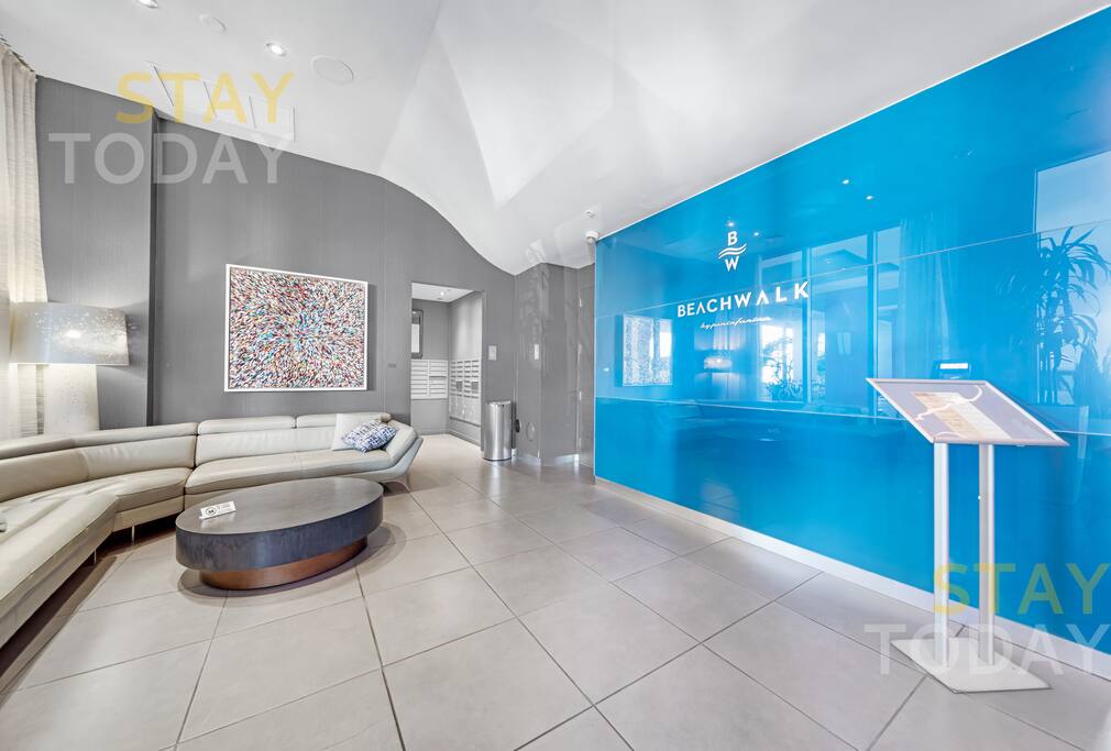 Stylish waiting area near the front desk, featuring a sleek, glossy finish and modern aesthetic. Unwind on a cozy couch in this elegant space, designed for comfort and relaxation.