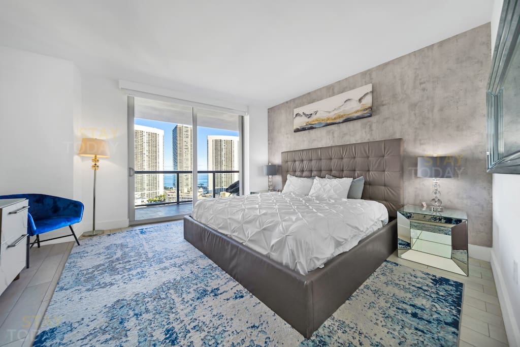 Spacious & Serene – A wide-angle view of the master bedroom showcases its airy layout and elegant blue-toned floor design. A tranquil retreat designed for ultimate comfort! 
