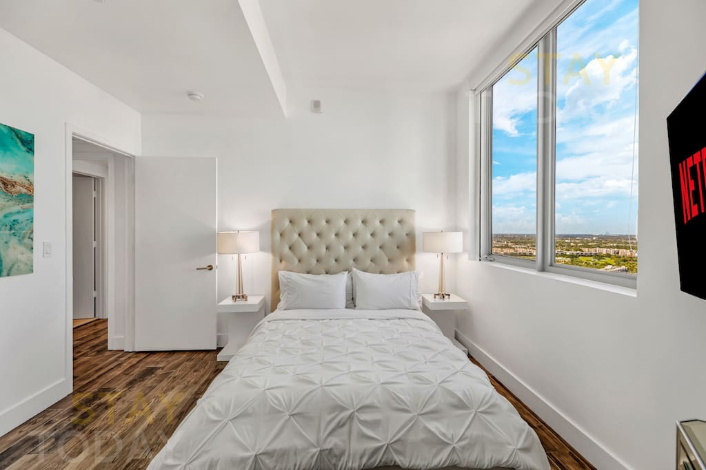 Captured at eye level, this view of the queen bed showcases its full elegance, from the footboard to the headboard. With its soft bedding and cozy setup, this space is designed for ultimate relaxation.