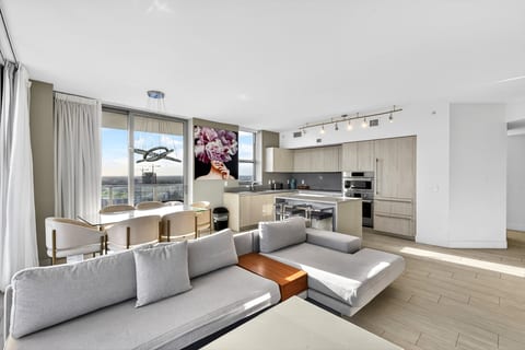 Sunlit open-plan condo with chef’s kitchen, balcony, and skyline views.