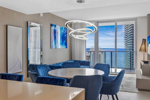 Gather around the round dining table surrounded by plush blue chairs, where modern elegance meets comfort. Large windows offer stunning ocean views, creating the perfect setting for meals and memorable conversations.