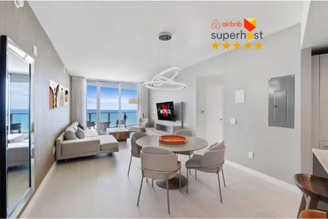 The dining area sits at the center of the open layout, offering a stylish round table and a bright setting for meals with an ocean backdrop.