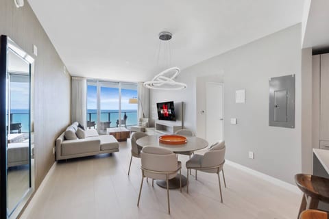 The dining area sits at the center of the open layout, offering a stylish round table and a bright setting for meals with an ocean backdrop.