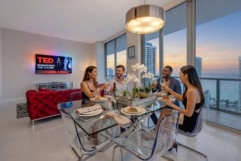 The glass dining table with seating for 6 people seamlessly blends with the living room, offering a sophisticated touch. Stunning lighting fixtures elevate the space, making every meal feel special.