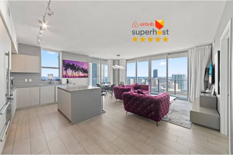 Enjoy an open-plan living space with a sleek kitchen and dining area. Large windows fill the room with natural light and offer expansive city and ocean views, creating a bright and inviting atmosphere for your stay.